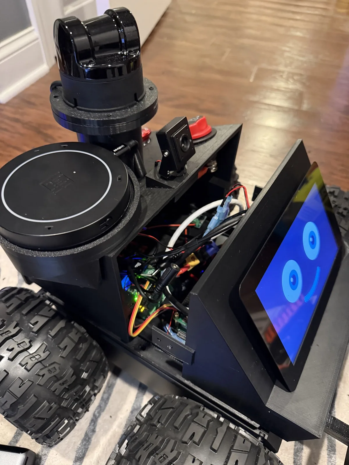 Inside Roger: a tangle of wiring, the Raspberry Pi and controller boards, the red emergency-stop switch, the microphone array and lidar mount, all packed into the printed enclosure