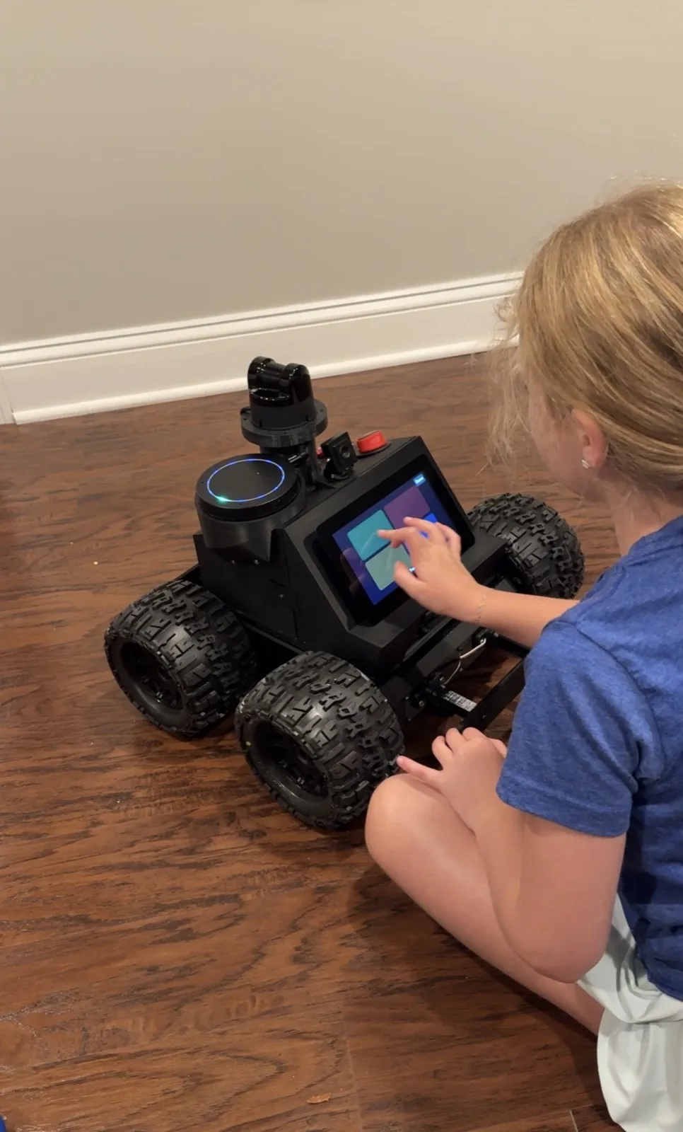 A child kneeling on the floor, tapping the screen on Roger's front to play tic-tac-toe